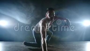现代芭蕾，一个人从舞台上的一个坐姿，在黑暗的舞台上旋转跳空跟